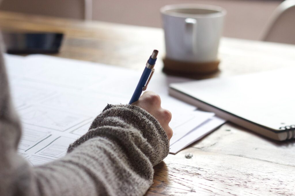 Writing on a notepad with coffee mug on a desk