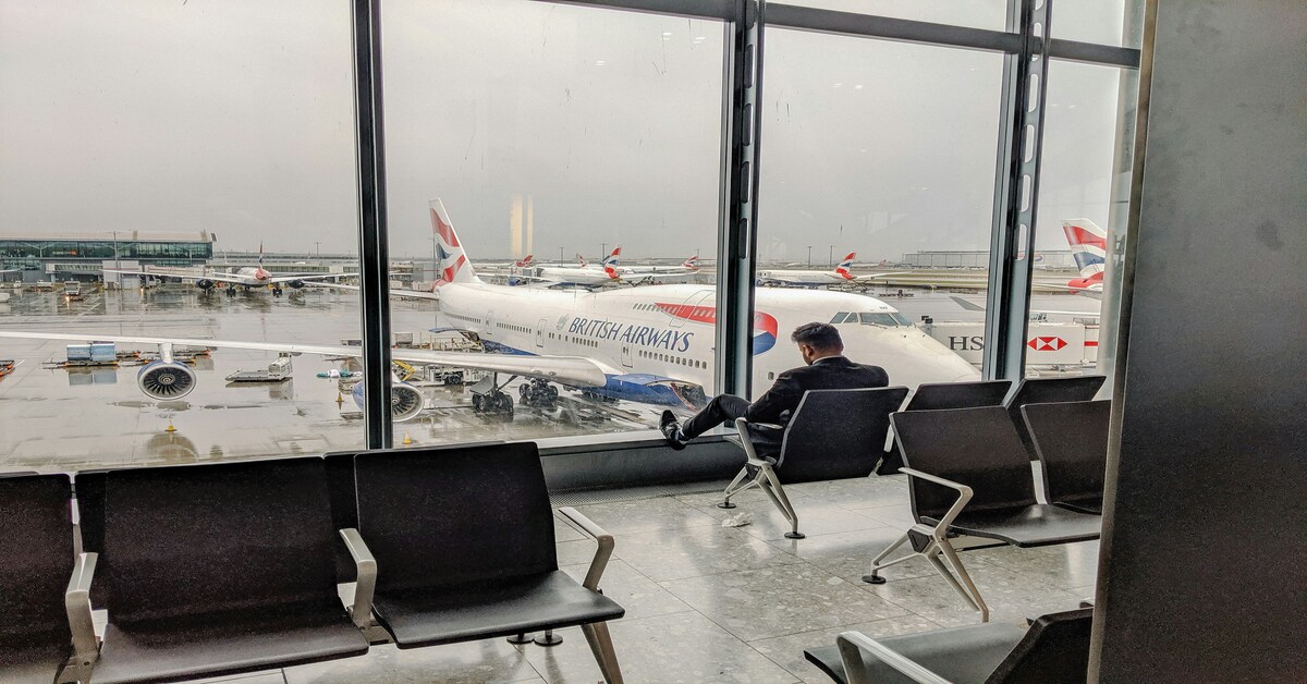 man waiting on flight to UK with plane in background - UK Visa Types